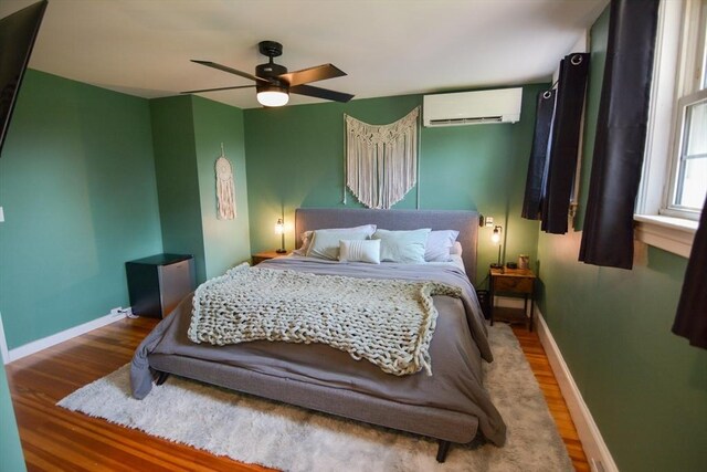 bedroom featuring hardwood / wood-style flooring, a wall mounted air conditioner, and ceiling fan