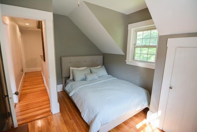 bedroom with light wood-type flooring, ceiling fan, and vaulted ceiling