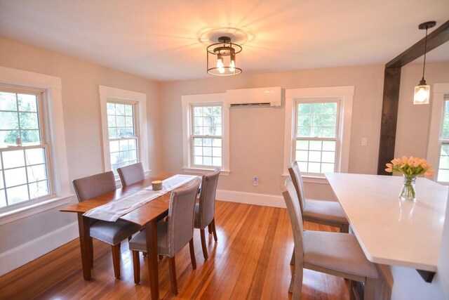 kitchen with an AC wall unit, light wood-type flooring, kitchen peninsula, gray cabinets, and pendant lighting