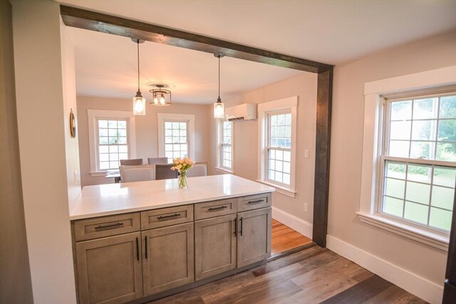 dining area featuring a wall mounted AC, wood-type flooring, and a healthy amount of sunlight