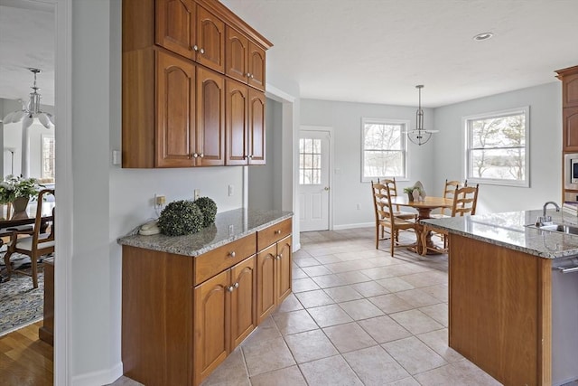 267 Barnes Rd, Oak Bluffs, MA 02557 - kitchen featuring light tile patterned floors, a sink, brown cabinetry, and light stone counters