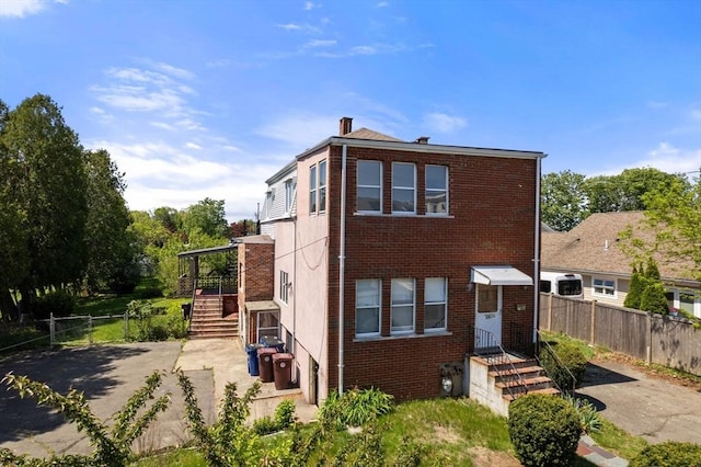 view of front of property with brick siding, a chimney, and fence