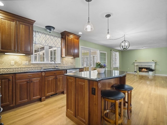 kitchen featuring a sink, light wood-style floors, a center island, decorative backsplash, and open floor plan
