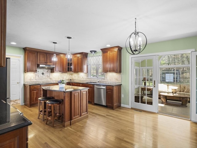 kitchen with stainless steel dishwasher, light wood-type flooring, an inviting chandelier, decorative backsplash, and decorative light fixtures