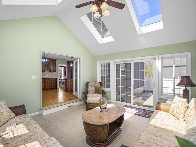 living room with tile patterned flooring, a skylight, high vaulted ceiling, and a ceiling fan