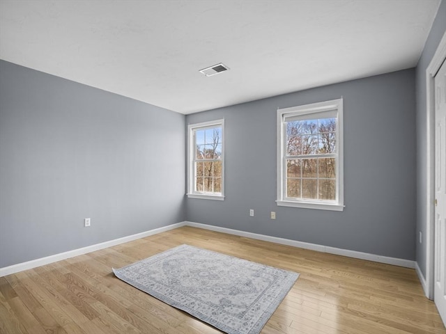 unfurnished room with visible vents, light wood finished floors, and baseboards