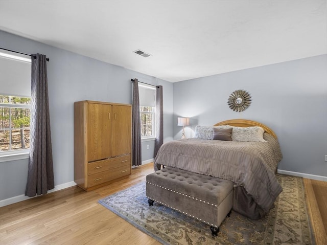 bedroom featuring baseboards, light wood-style flooring, and visible vents