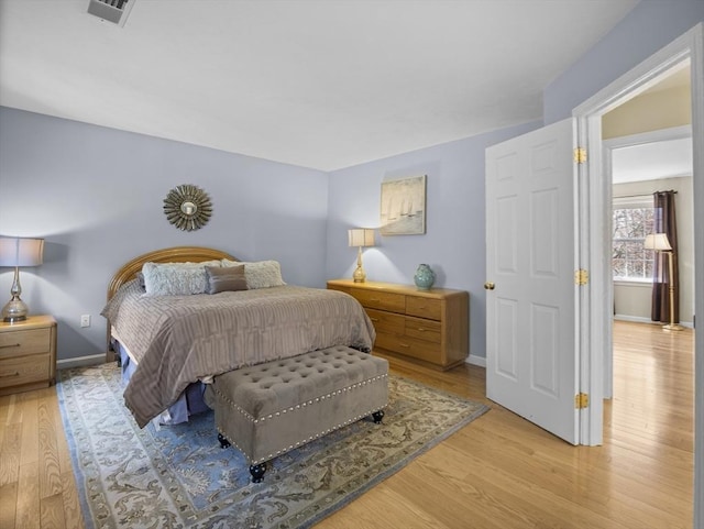 bedroom with baseboards, light wood-style flooring, and visible vents