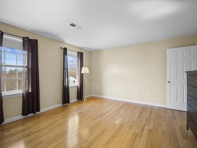 unfurnished room with light wood finished floors, baseboards, and visible vents