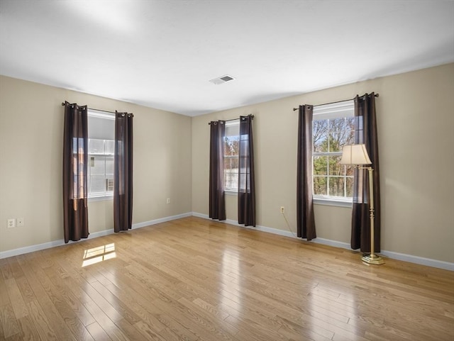 unfurnished room with light wood finished floors, baseboards, and visible vents