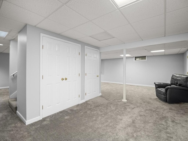 finished basement featuring a paneled ceiling, carpet flooring, and baseboards