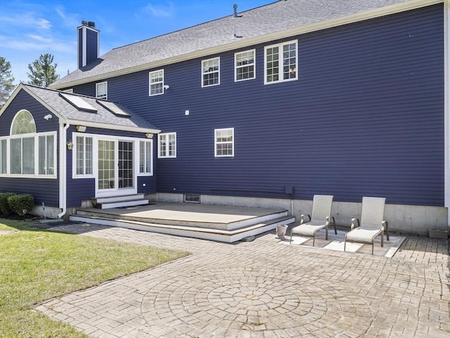 back of property featuring a chimney, entry steps, a yard, and a patio