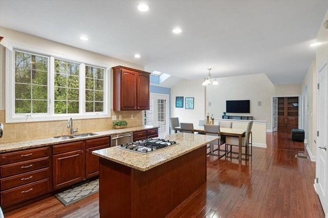 kitchen with a center island, a sink, stainless steel appliances, dark wood finished floors, and a chandelier