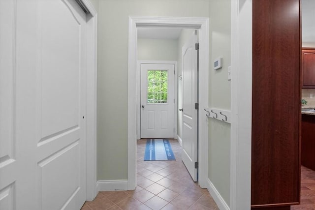 corridor with baseboards and light tile patterned floors
