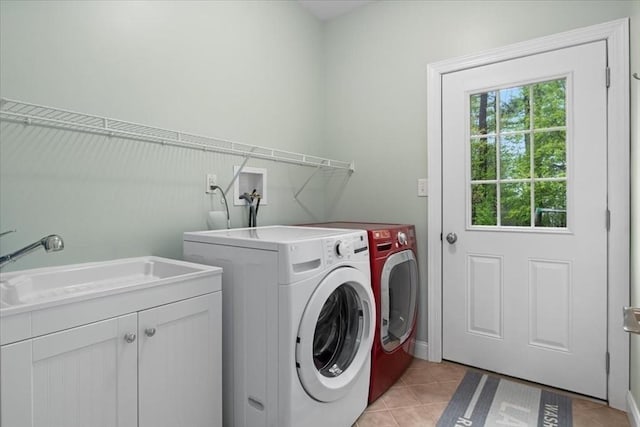 washroom featuring cabinet space, washing machine and clothes dryer, light tile patterned floors, and a sink