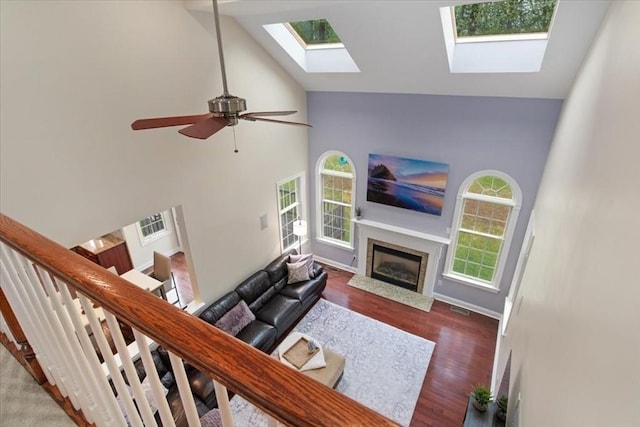 living room featuring a fireplace with flush hearth, a healthy amount of sunlight, high vaulted ceiling, and a skylight