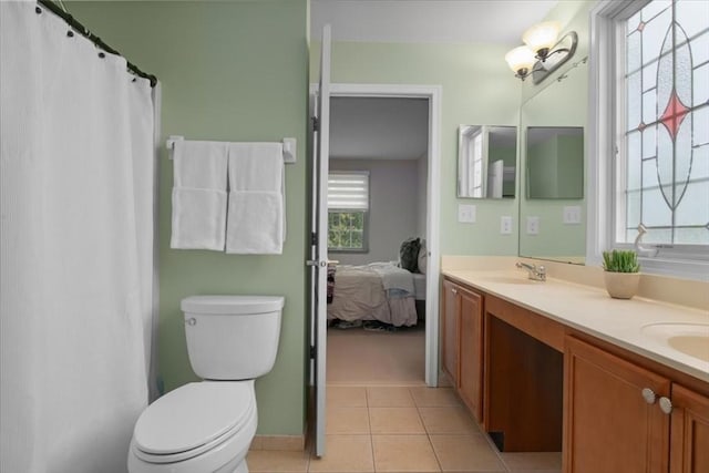 ensuite bathroom featuring a sink, double vanity, toilet, and tile patterned floors