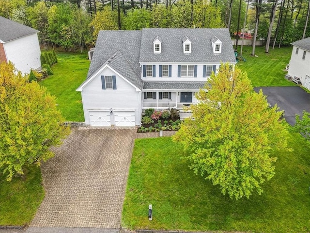 view of front of house with a porch, a shingled roof, decorative driveway, and a front yard