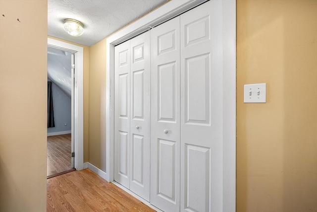 hall with light hardwood / wood-style floors and a textured ceiling