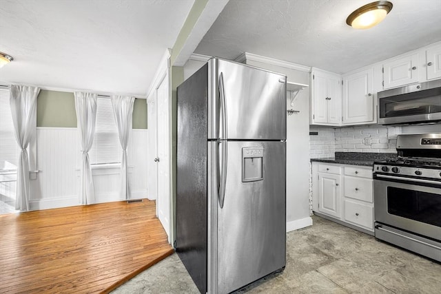 kitchen with white cabinets, backsplash, crown molding, and stainless steel appliances