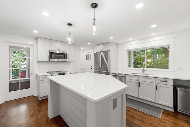 kitchen with appliances with stainless steel finishes, decorative light fixtures, sink, and plenty of natural light