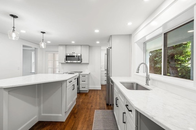 kitchen with sink, white cabinets, hanging light fixtures, light stone counters, and stainless steel appliances