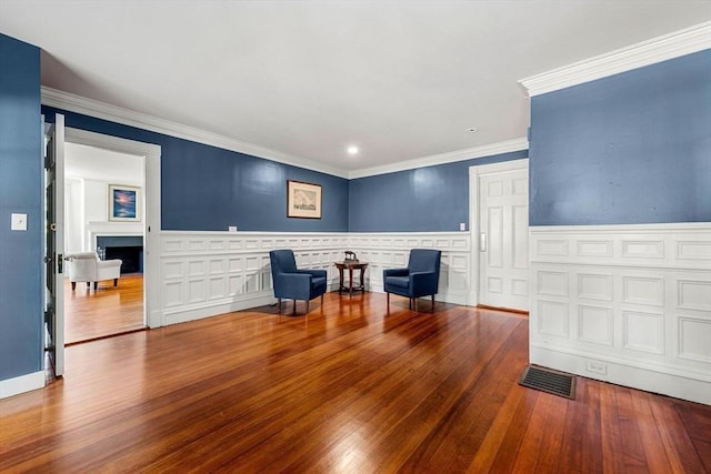 living area with crown molding and wood-type flooring