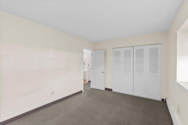 unfurnished bedroom with dark colored carpet, a closet, and a baseboard heating unit