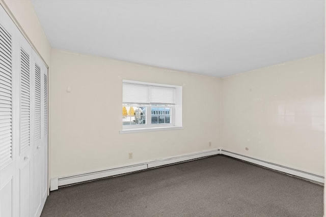 unfurnished bedroom featuring a baseboard heating unit, carpet floors, and a closet