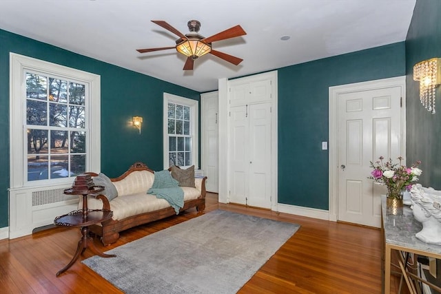 living area featuring baseboards, ceiling fan, and wood finished floors