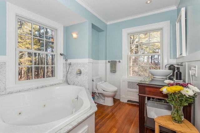 full bath featuring vanity, toilet, a jetted tub, wood finished floors, and ornamental molding