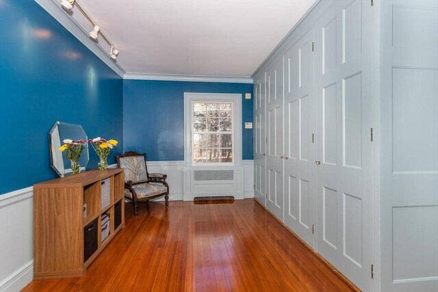 living area featuring crown molding, wainscoting, rail lighting, and wood finished floors