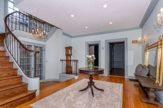 foyer with ornamental molding, recessed lighting, wood finished floors, and a notable chandelier