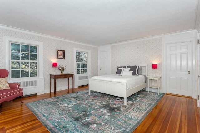 bedroom with crown molding, wood finished floors, and wallpapered walls