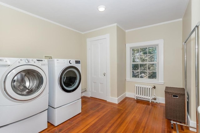 laundry area featuring washing machine and clothes dryer, laundry area, radiator heating unit, wood finished floors, and ornamental molding
