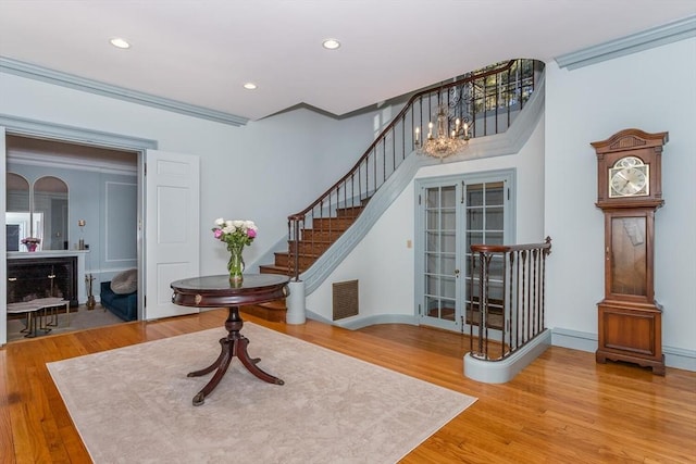 entrance foyer with an inviting chandelier, stairway, wood finished floors, and visible vents