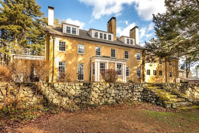 back of house featuring a chimney and stucco siding