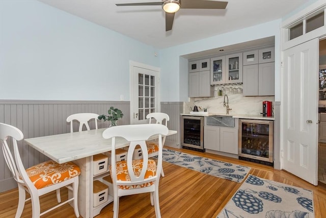 interior space featuring wine cooler, a ceiling fan, indoor wet bar, and wainscoting
