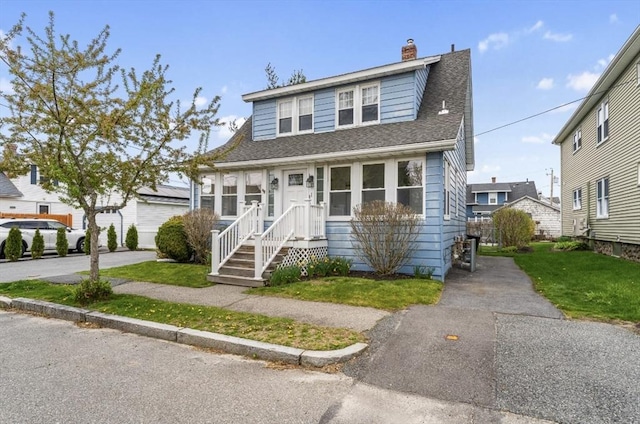 view of front of property with a chimney, roof with shingles, and a front yard
