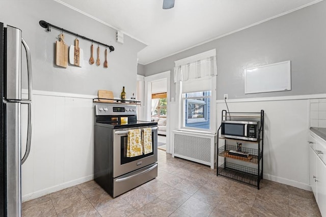 kitchen with stainless steel appliances, crown molding, and wainscoting