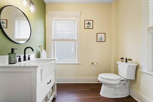 bathroom with vanity, toilet, wood finished floors, and baseboards