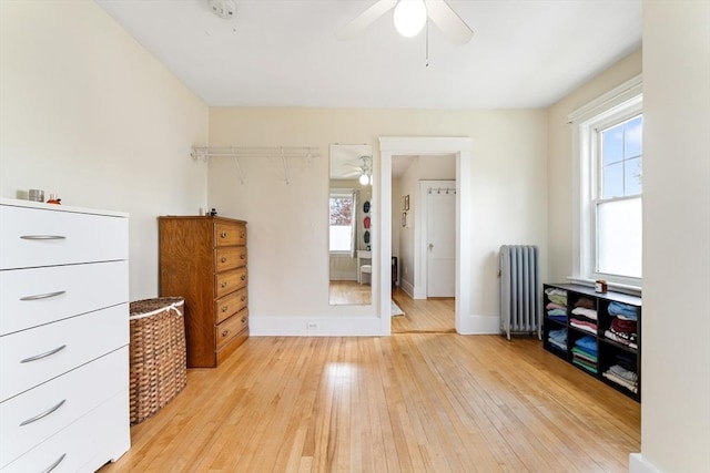 bedroom with radiator heating unit, light wood-style flooring, baseboards, and a ceiling fan