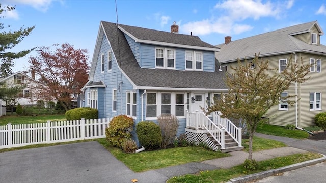view of front of property featuring fence, a shingled roof, and a chimney