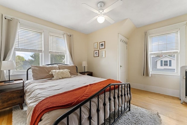 bedroom with light wood finished floors, multiple windows, and baseboards