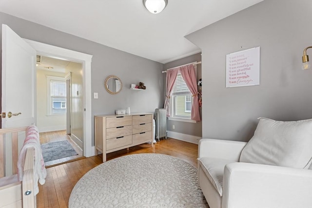 living area featuring radiator, healthy amount of natural light, wood-type flooring, and baseboards