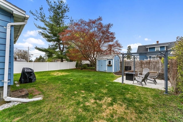 view of yard featuring a storage unit, a fire pit, a patio area, and an outbuilding
