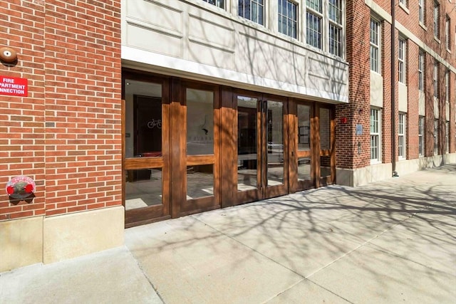 view of exterior entry featuring brick siding and french doors
