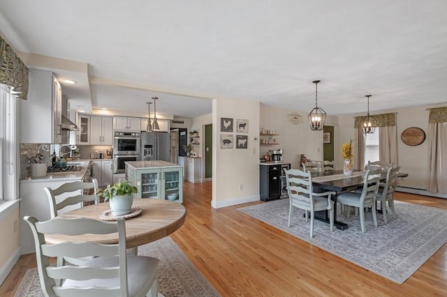 dining area featuring baseboards, light wood-style flooring, and beverage cooler