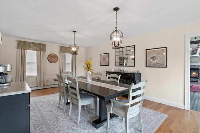 dining space featuring light wood-style floors, baseboards, baseboard heating, and a wealth of natural light