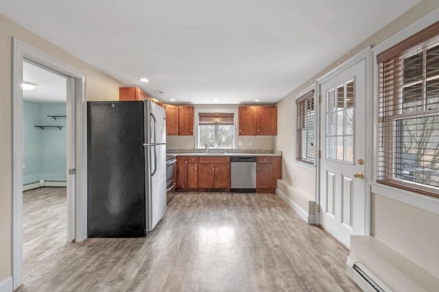 kitchen featuring brown cabinetry, appliances with stainless steel finishes, a sink, a baseboard heating unit, and light wood finished floors